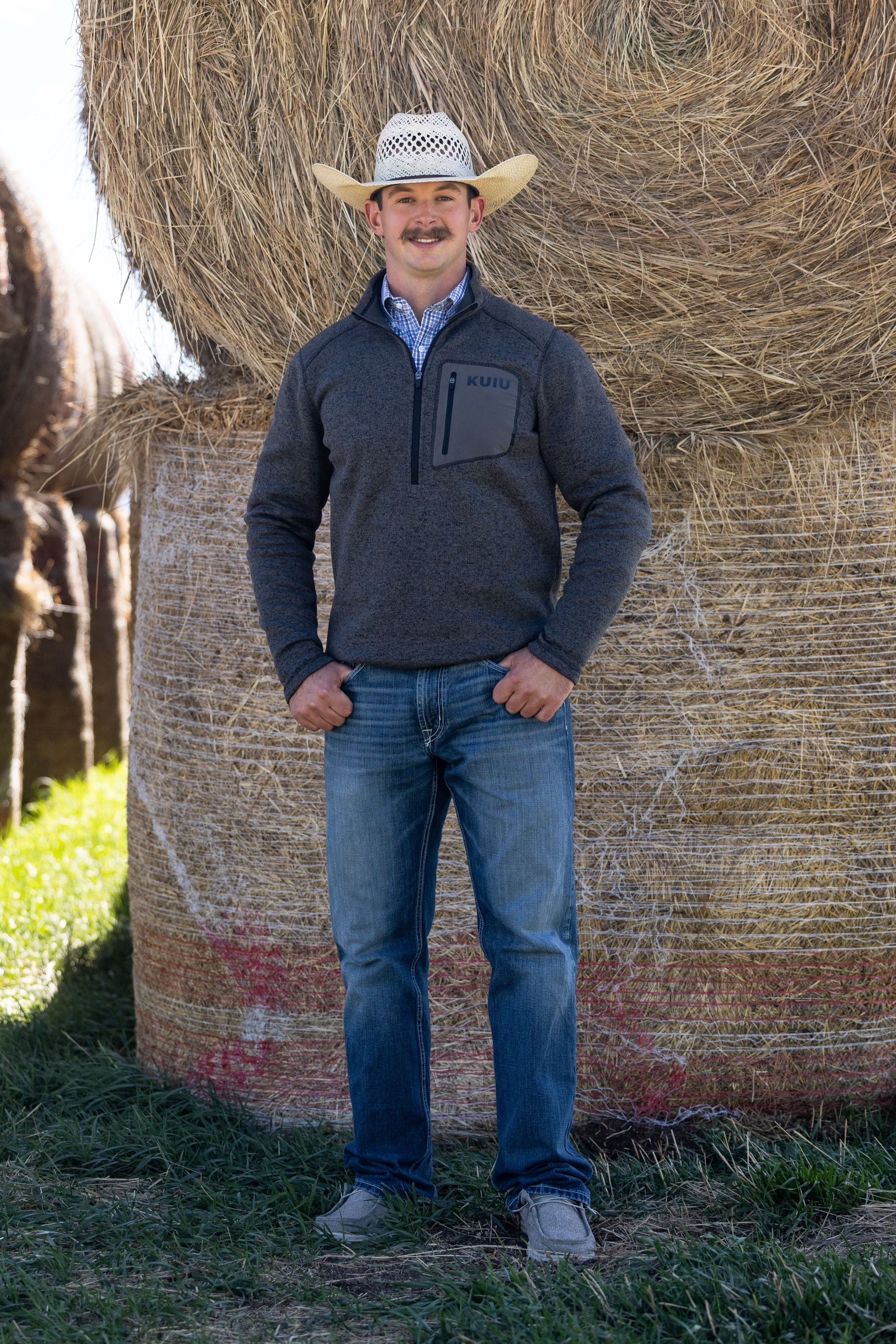 a man standing in front of a hay bale