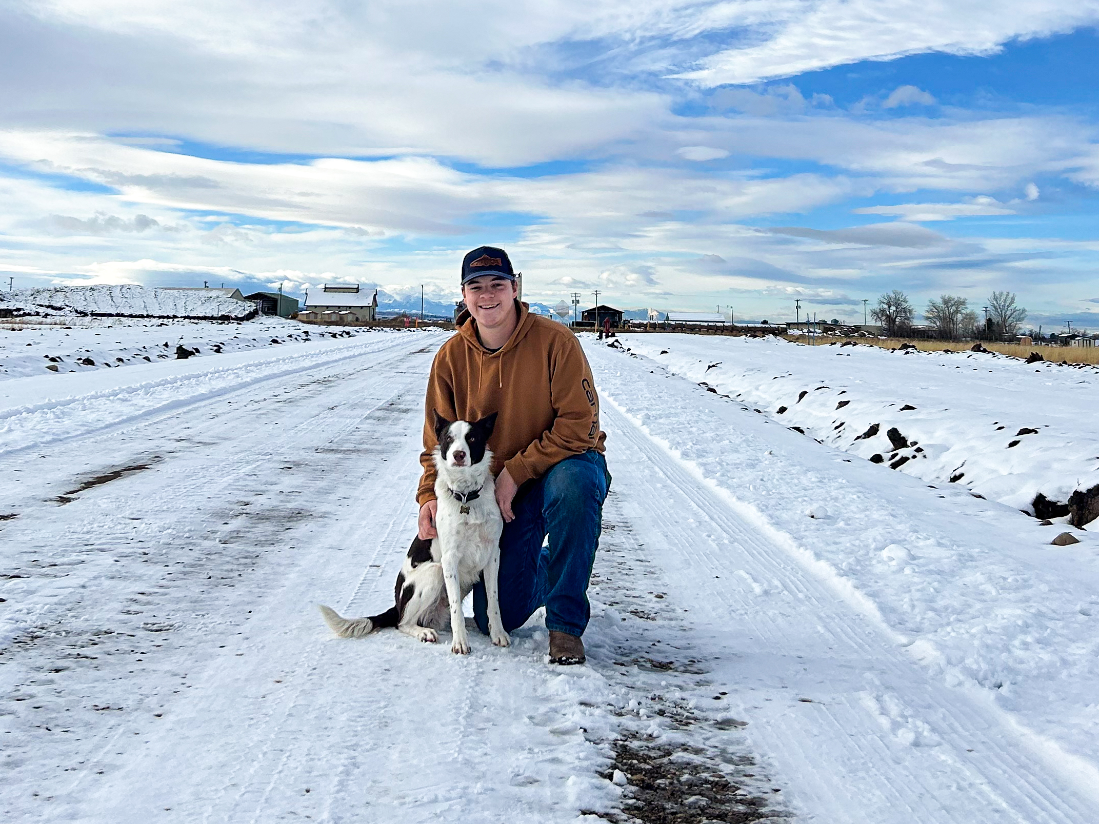 a young man with a dog and mountains in the backgroun