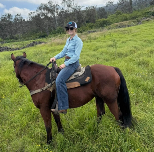 A young woman wearing a cap on horseback
