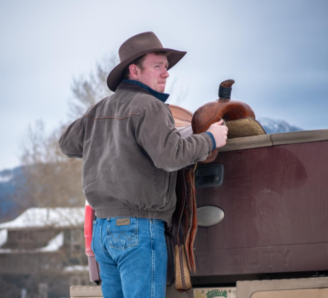 a young man saddling a horse