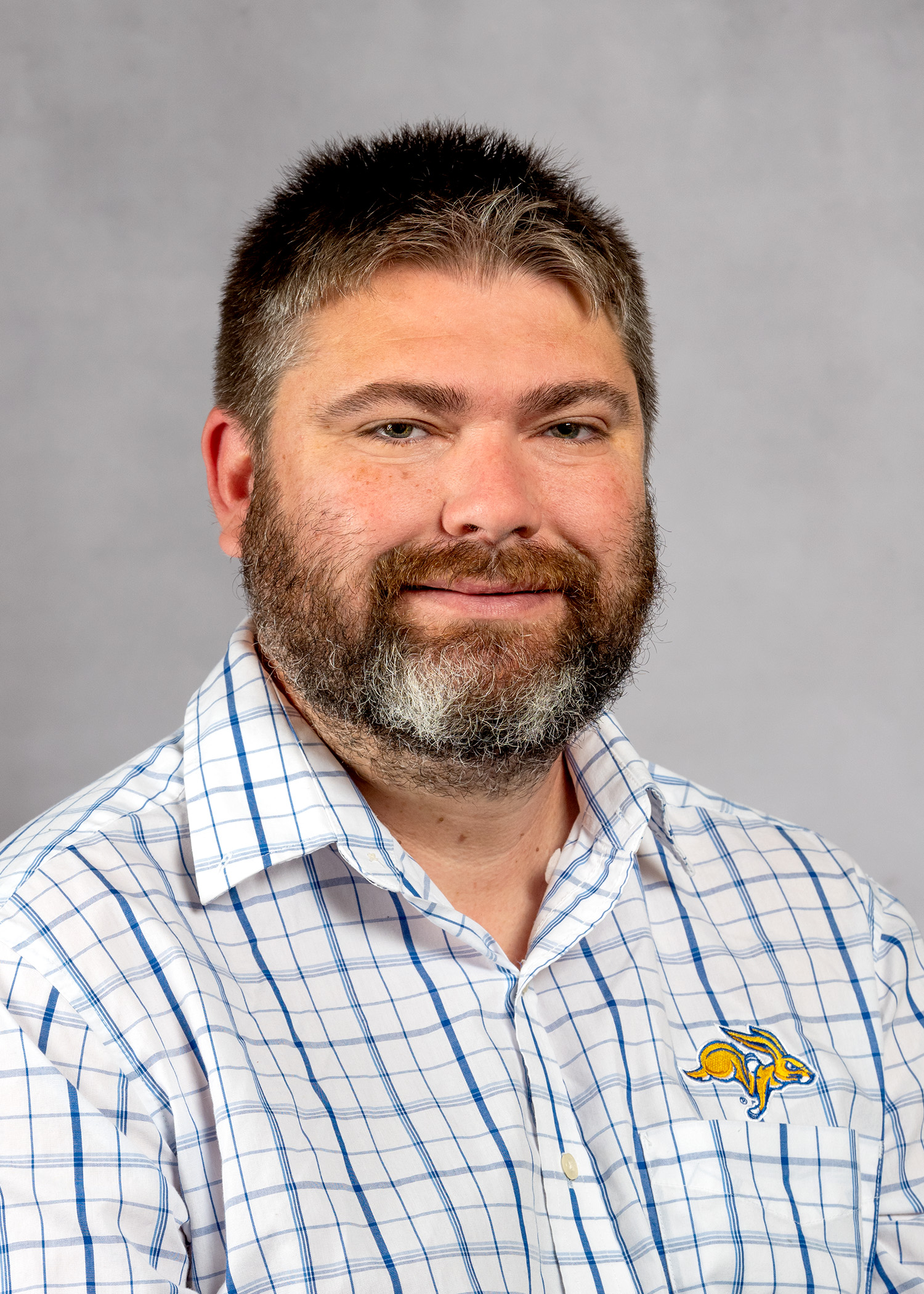 Man with short hair and a beard wearing a plaid shirt