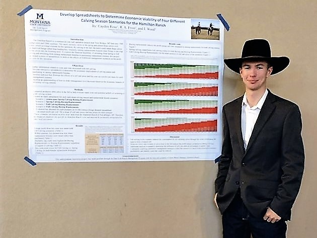 young man in hat next to a research poster