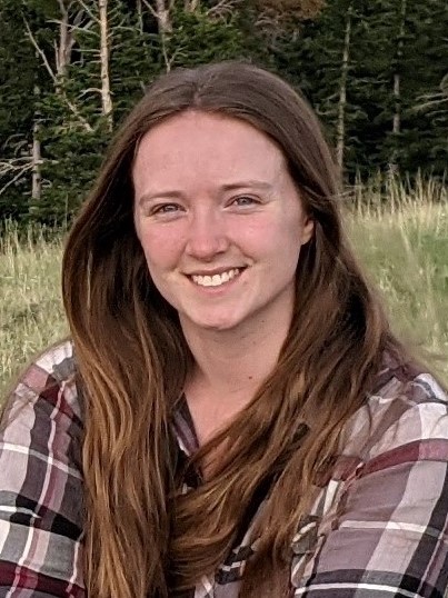 A woman with long brown hair in a plaid shirt