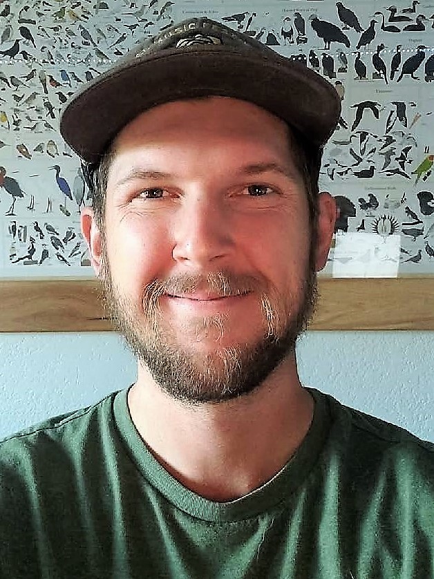 Smiling man with close-cropped hair wearing a baseball cap