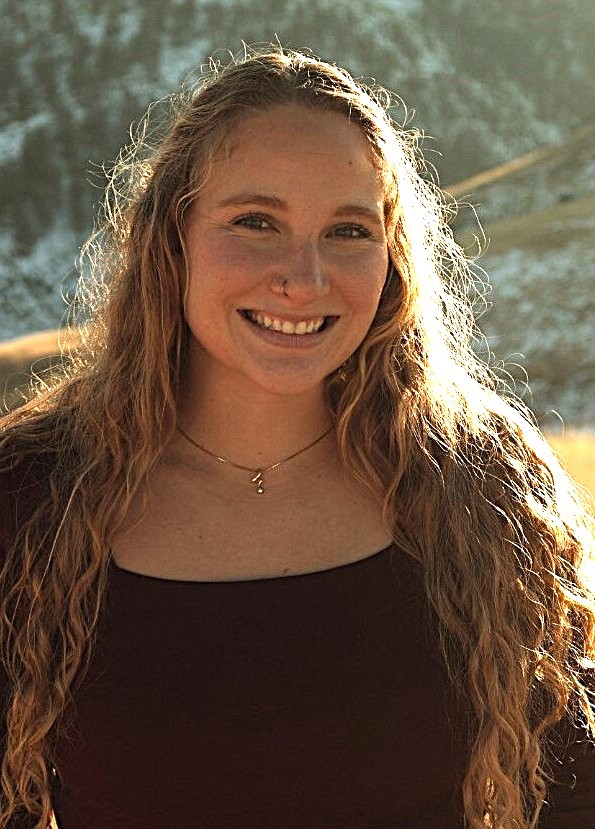 a young woman with long wavy hair posed in an alpine meadow.