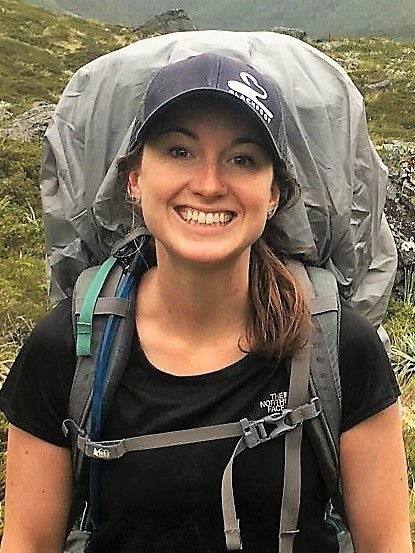 Woman wearing a cap and a backpack in smiling in the outdoors